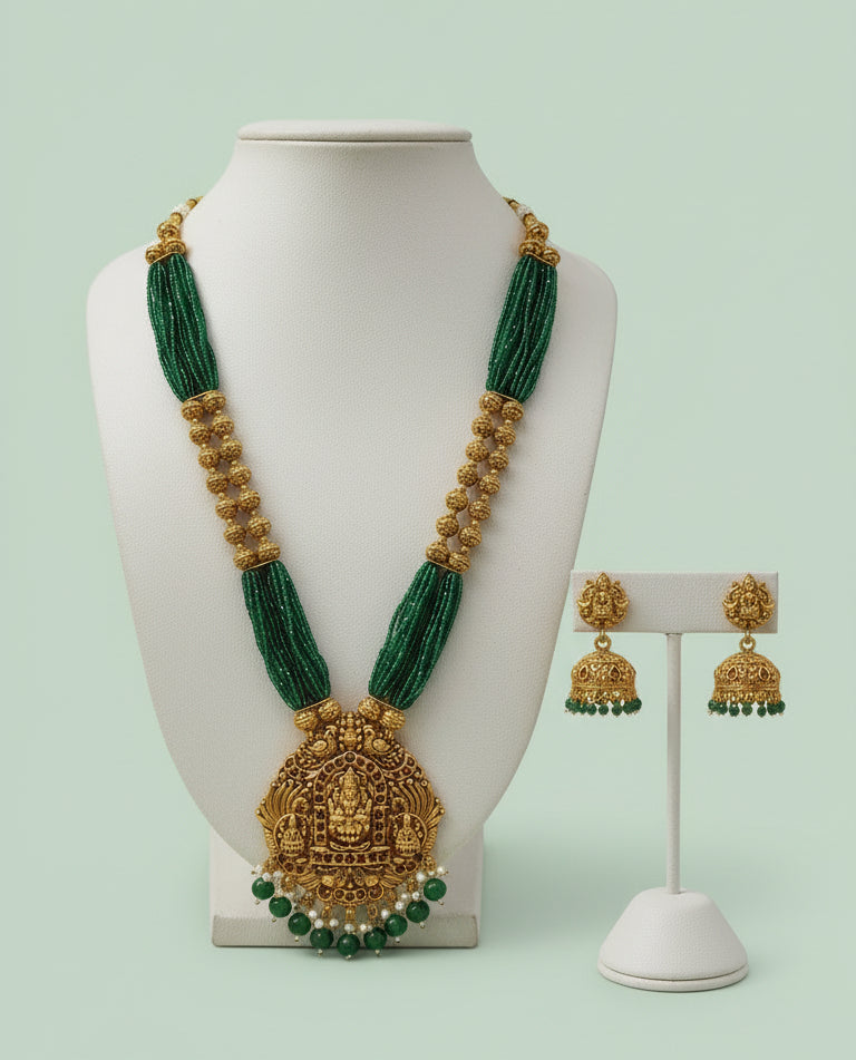 Green and gold necklace with matching earrings on a mannequin and stand against a light green background