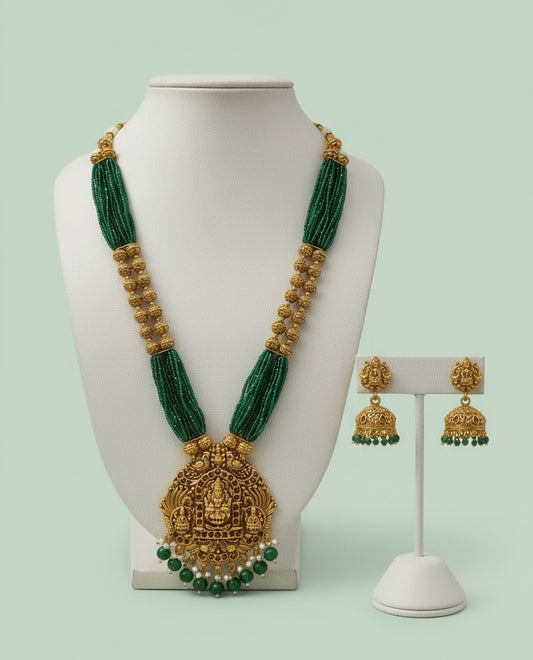 Green and gold necklace with matching earrings on a mannequin and stand against a light green background