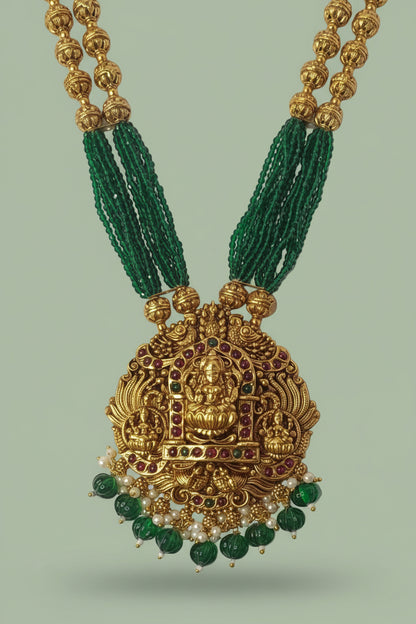 Gold necklace with green beads on a light green background