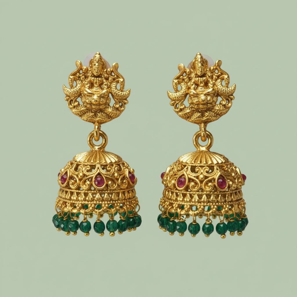 Gold earrings with green and red gemstones on a light green background