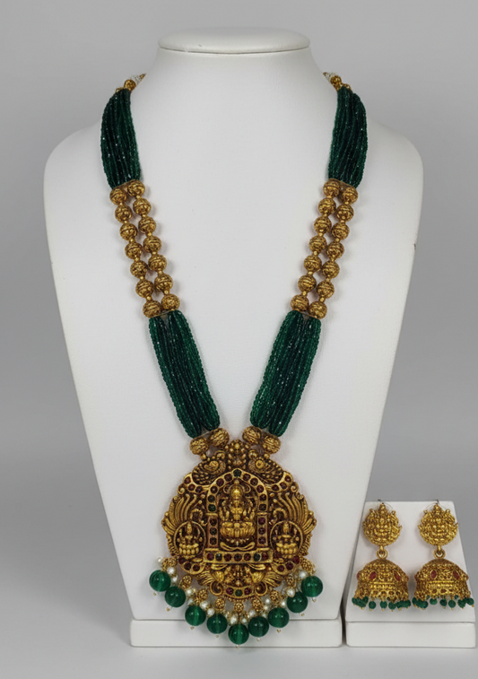 Green and gold necklace with matching earrings on a white mannequin.