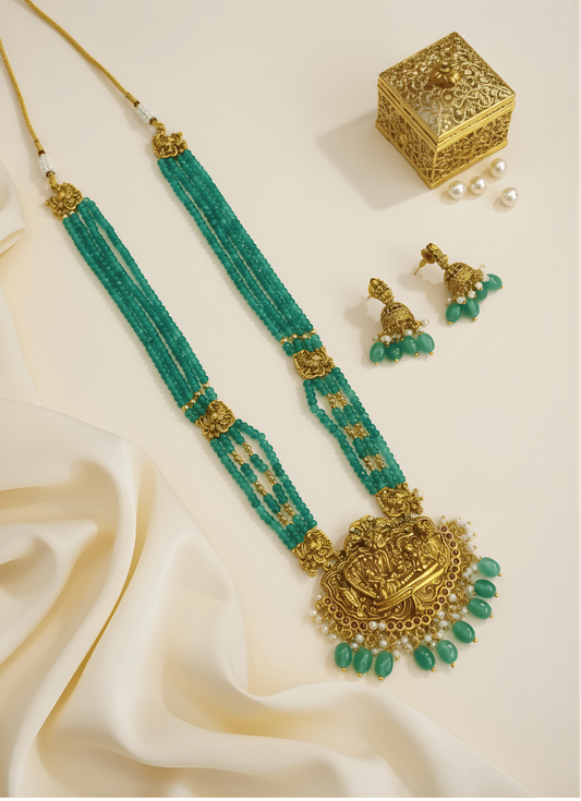 Green and gold bead necklace set on a cream background