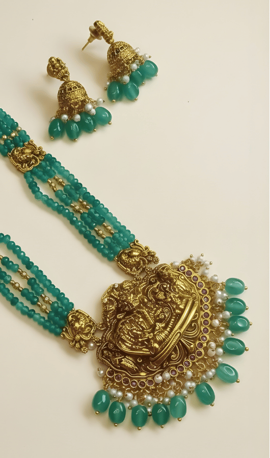 Turquoise necklace with gold and pearl accents and matching earrings on a cream background