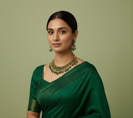 Woman wearing a green saree with jewelry against a green background