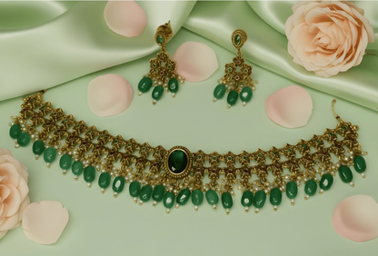 Gold and green jewelry set with roses and a perfume bottle on a green satin background