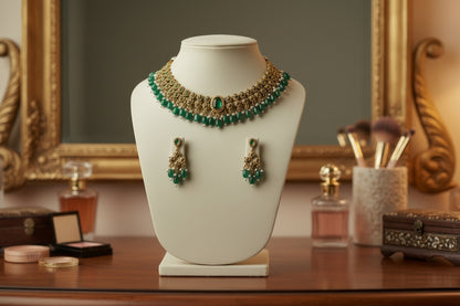 Gold and green necklace with matching earrings on a mannequin bust against a gray background