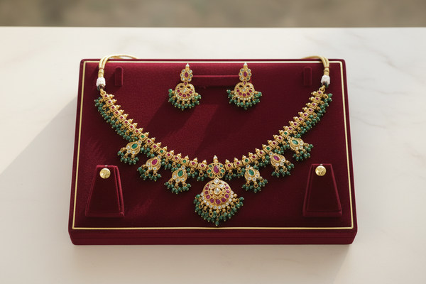 antique gold necklace with green enamel leaf motifs, ruby accents & a statement pendant