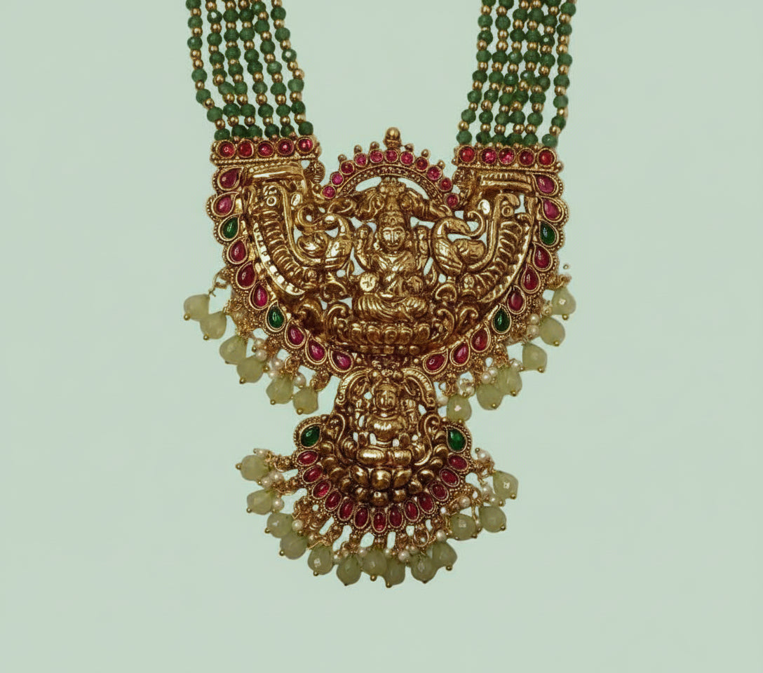 Ornate gold necklace with intricate designs on a light green background