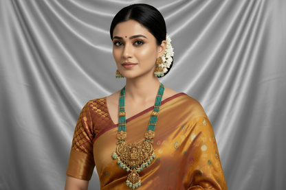 Woman wearing green bead south indian long necklace in a traditional saree with a light green background