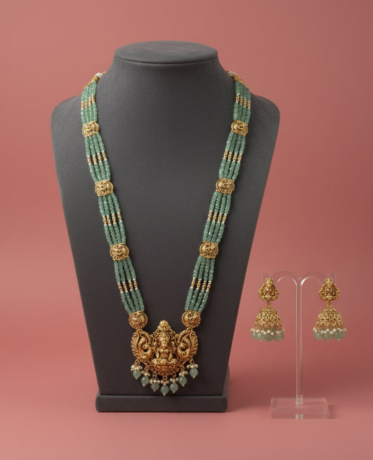 Jewelry set with a necklace and earrings on a mannequin and stand against a pink background