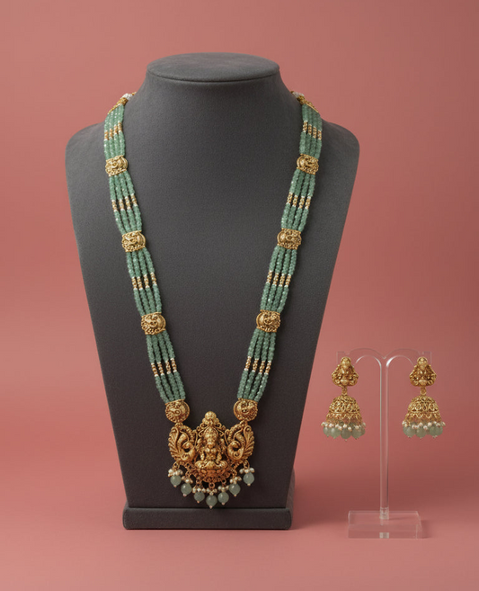 Jewelry set with a necklace and earrings on a mannequin and stand against a pink background
