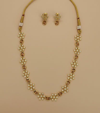 Gold necklace with floral designs and matching earrings on a white background