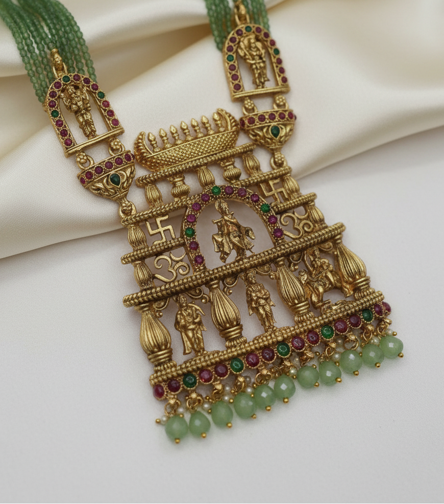 Ornate gold necklace with green beads on a white background