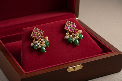 Pair of earrings with gemstones on a black stand against a dark background