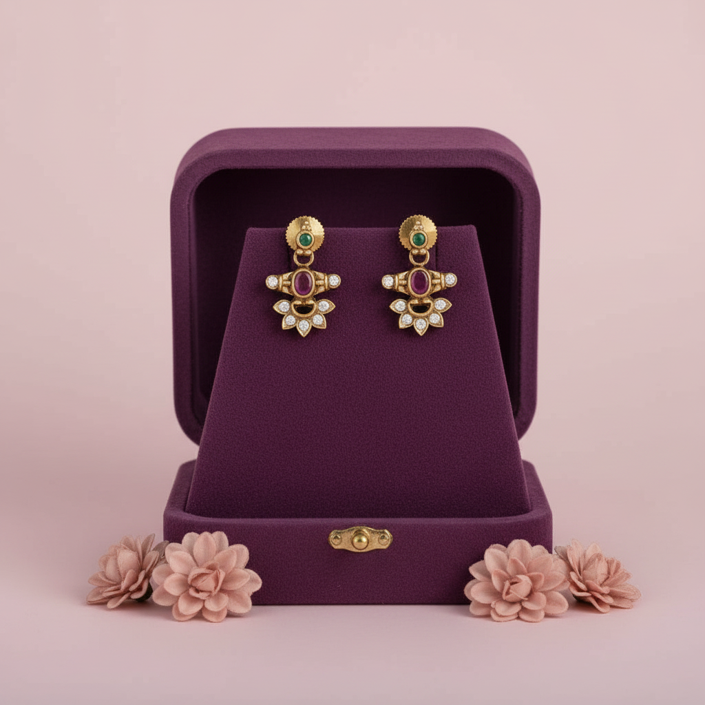 Pair of gold earrings with stones in a purple jewelry box on a pink background