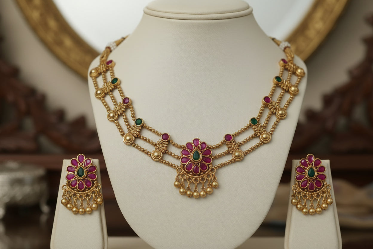 Gold necklace and earrings set on a mannequin bust against a gray background