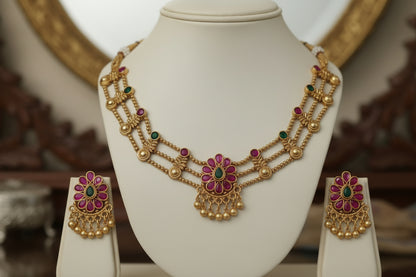 Gold necklace and earrings set on a mannequin bust against a gray background