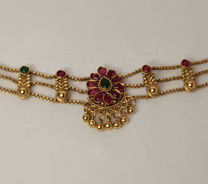 Gold bracelet with red gemstones on a light gray background