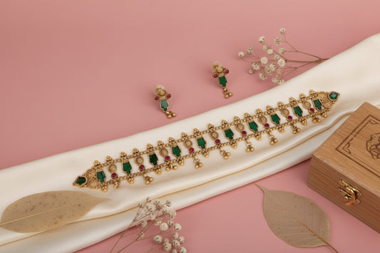 Gold jewelry set with emeralds and rubies on a pink background