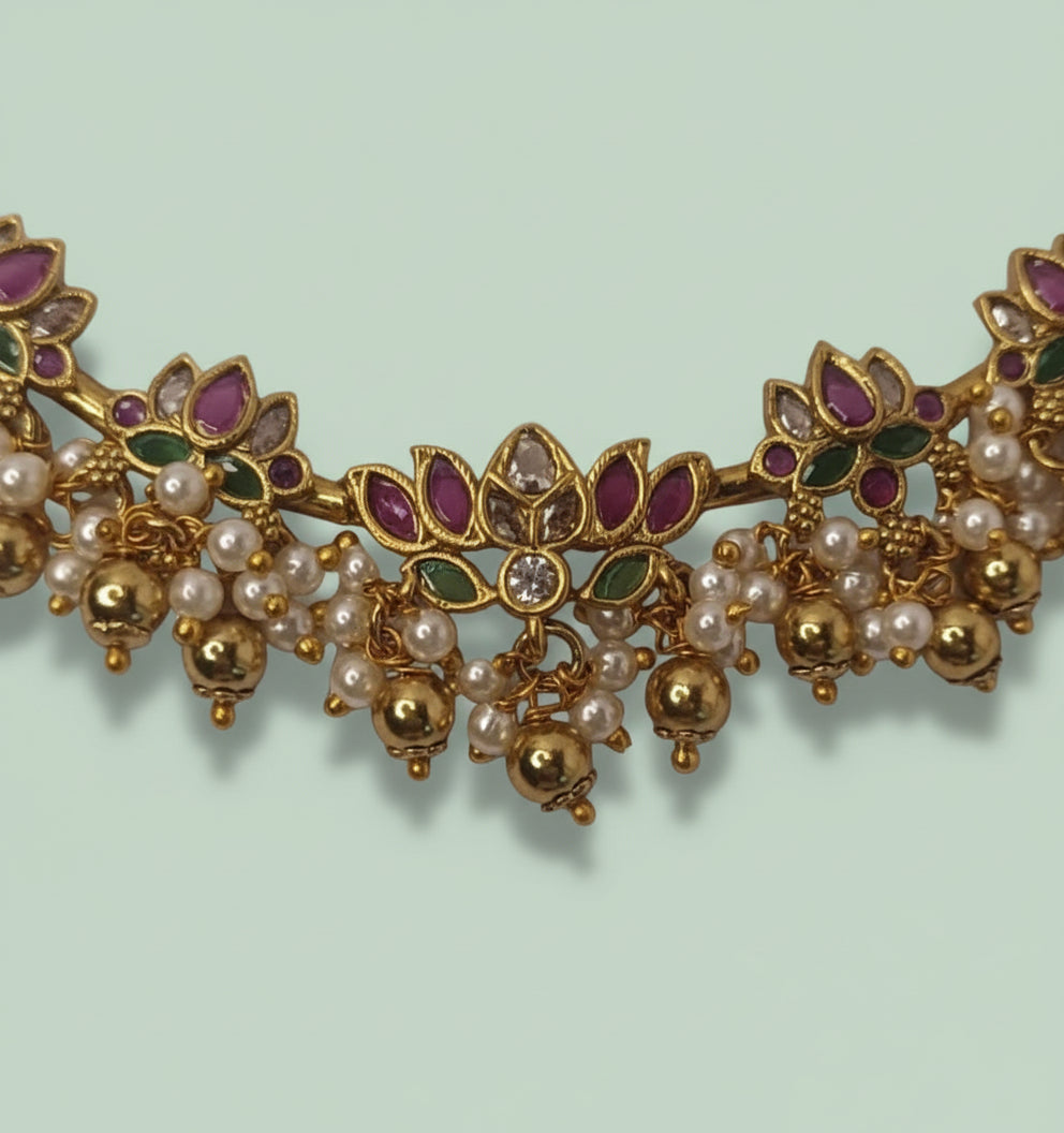 Ornate gold necklace with pearls and gemstones on a light green background