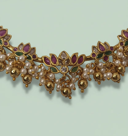 Ornate gold necklace with pearls and gemstones on a light green background