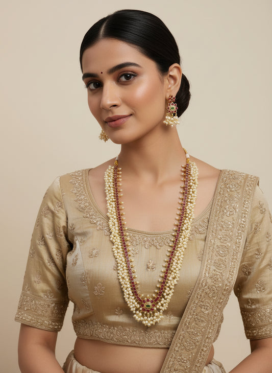 Pearl necklace with red accents and matching earrings on a white fabric background