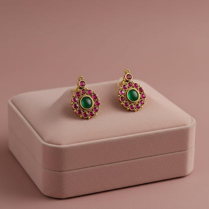 Pair of earrings with green gemstones on a white fabric background