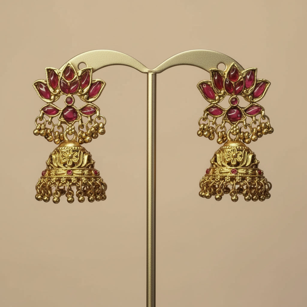 Gold earrings with red stones on a pink background