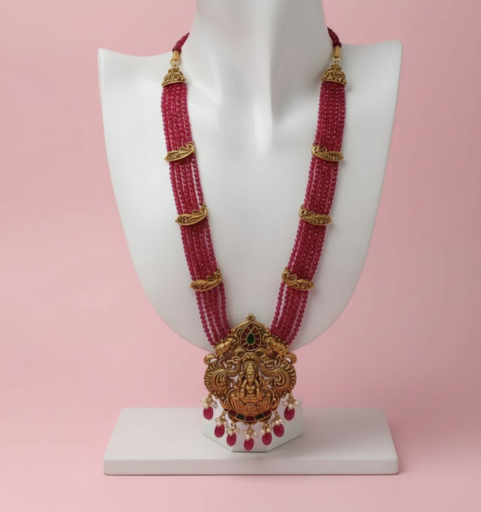 Ornate pink beaded necklace with gold accents on a white background