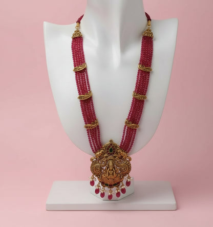 Ornate pink beaded necklace with gold accents on a white background