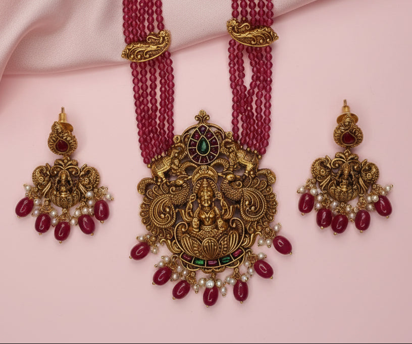 Gold and red jewelry set on a pink fabric background