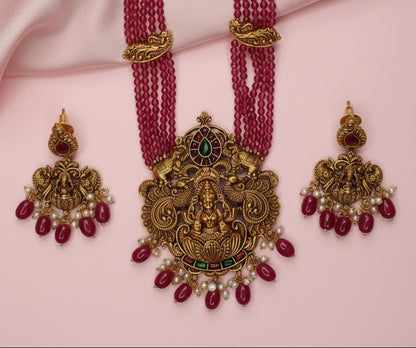 Gold and red jewelry set on a pink fabric background