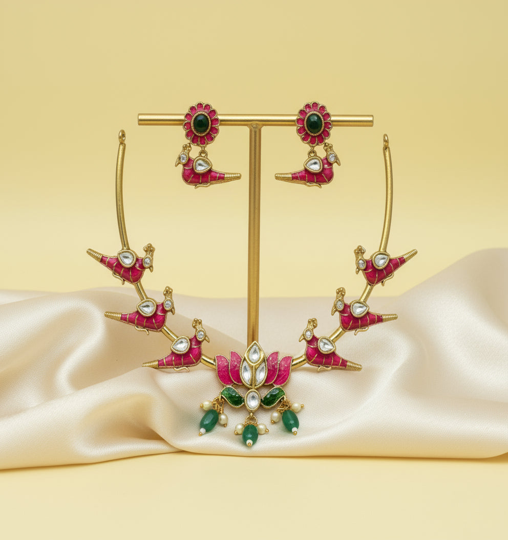 Ornate earrings with pink and green stones on a gold stand against a beige background