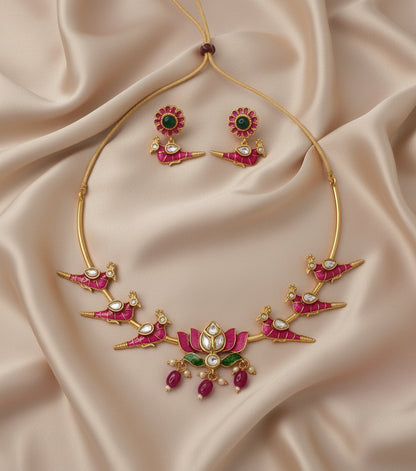 Gold necklace with pink and green gemstones on a beige fabric background