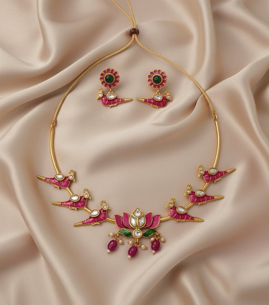 Gold necklace with pink and green gemstones on a beige fabric background