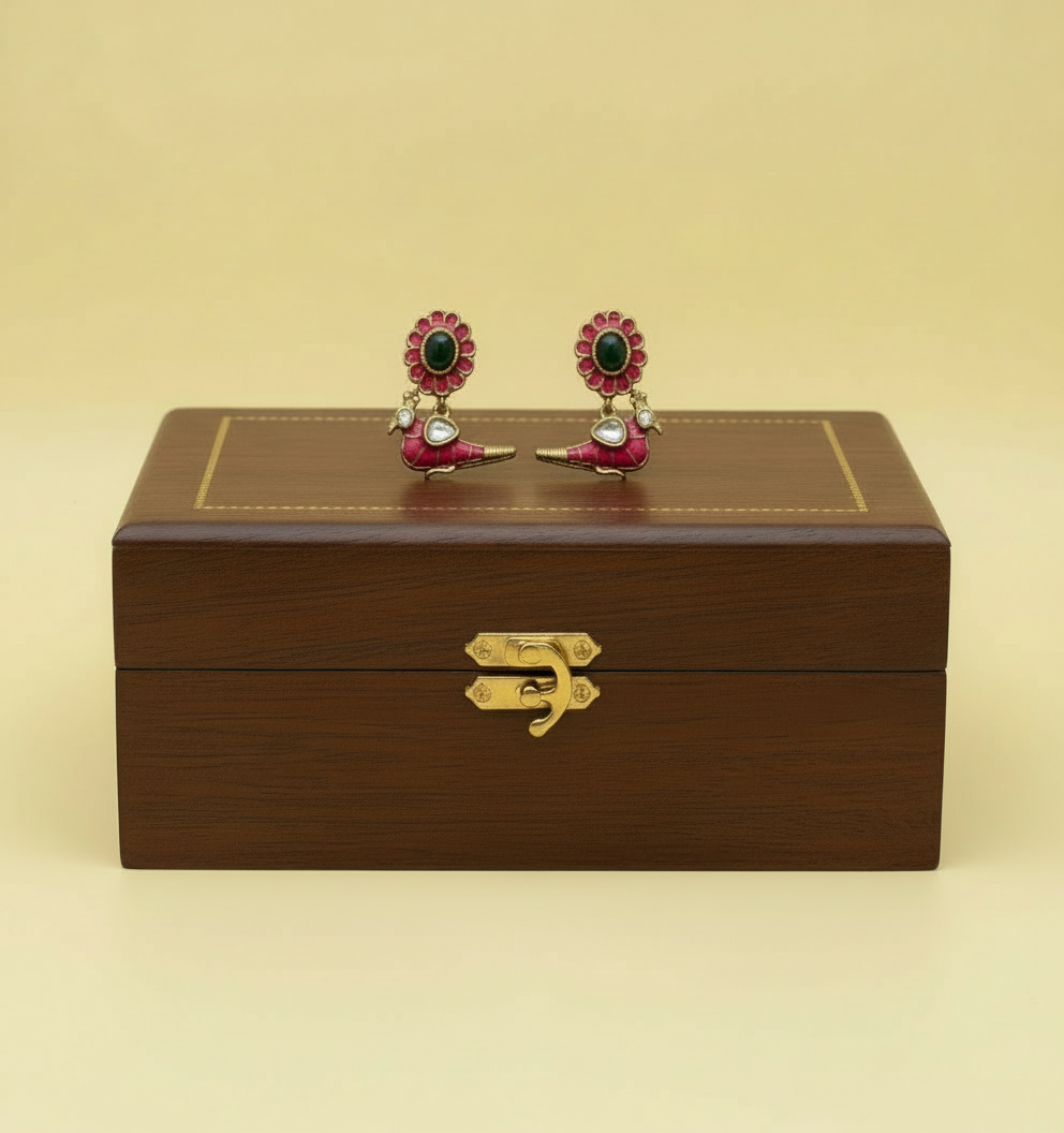 Jewelry box with a pair of earrings on top against a beige background