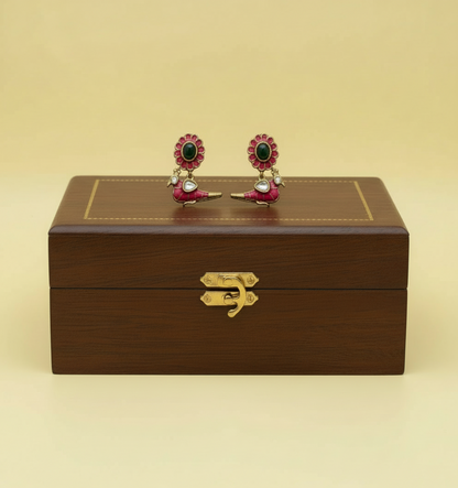 Jewelry box with a pair of earrings on top against a beige background