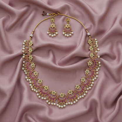 Ornate necklace and earrings set on a pink satin background