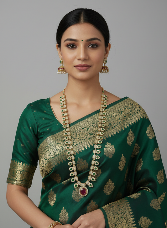 Woman wearing a green saree with gold patterns and jewelry on a gray background