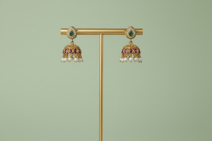 Gold jewelry stand with two pairs of earrings on a gray background
