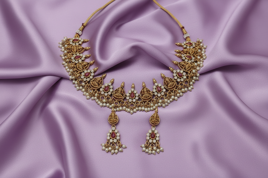 Ornate gold necklace with red stones on a beige fabric background