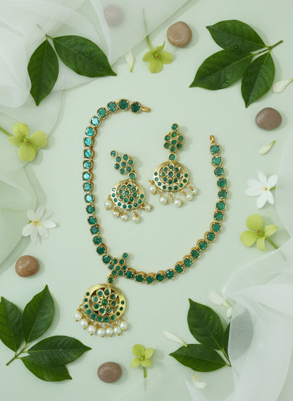 Green and gold jewelry set with leaves and flowers on a light background