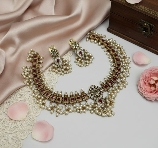 Ornate necklace with red stones and pearls on a soft fabric background