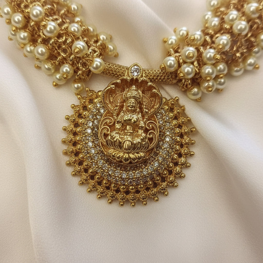 Gold necklace with a detailed pendant on a light pink background