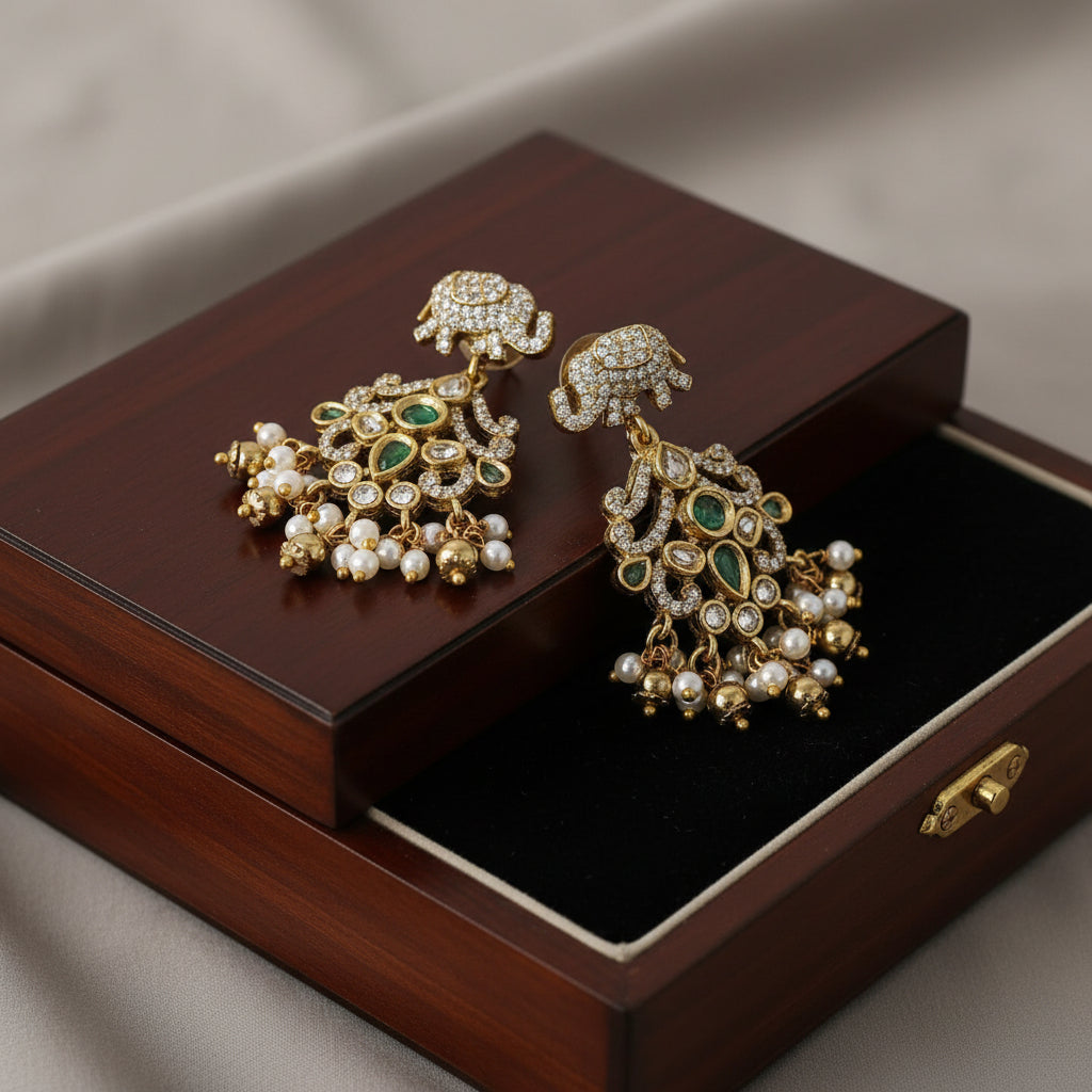 Ornate gold earrings with green stones on a wooden jewelry box.