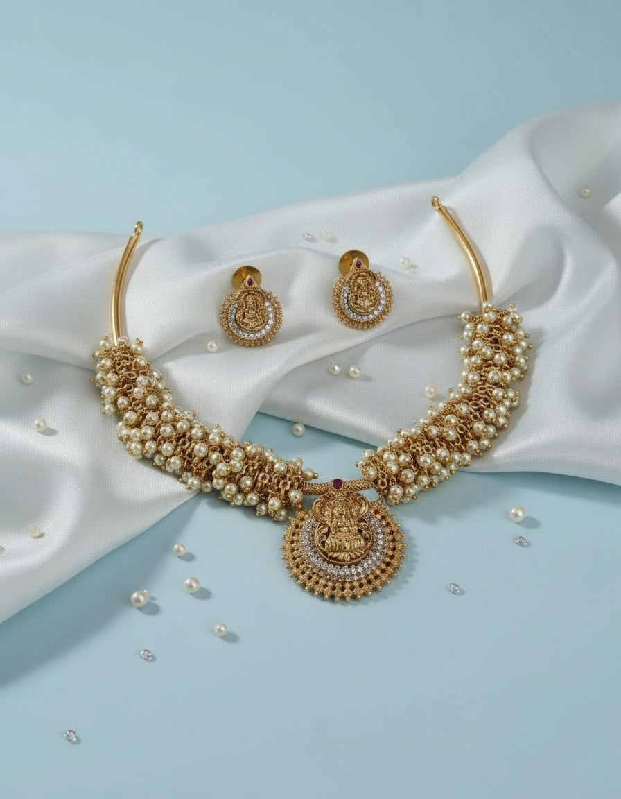 Gold necklace and earrings on a light blue fabric background