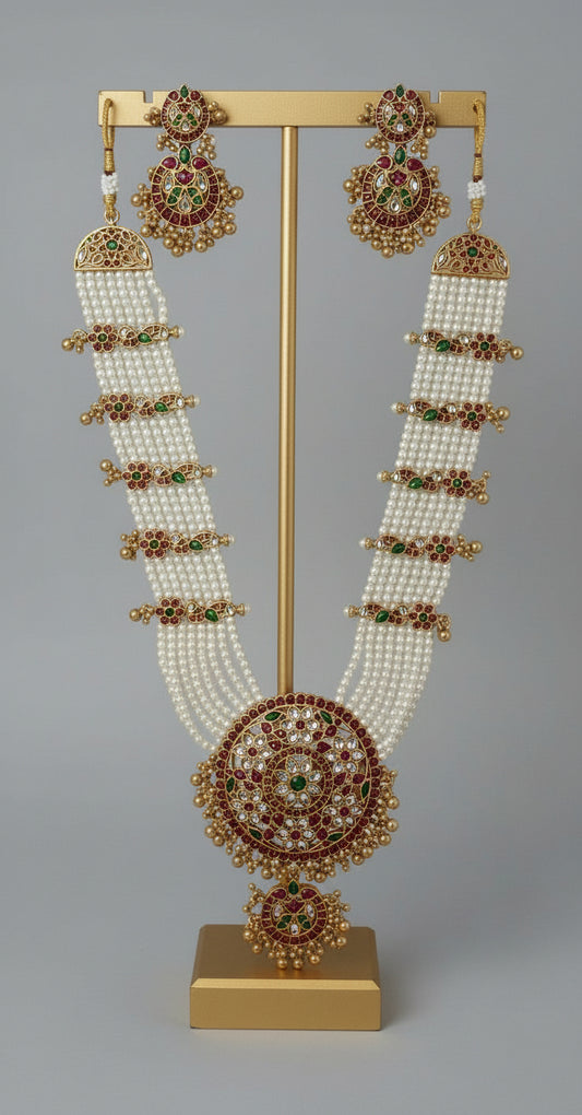 Ornate necklace and earrings on a gold stand against a gray background