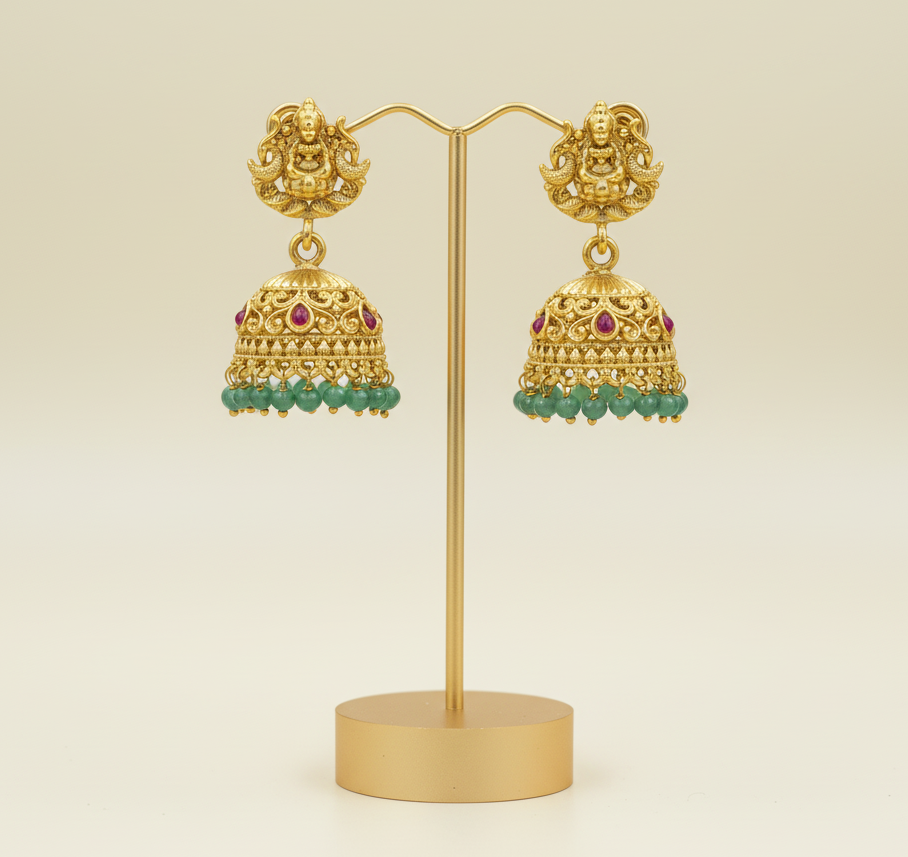 Gold earrings with intricate designs on a light green background