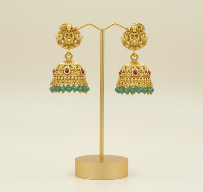 Gold earrings with intricate designs on a light green background