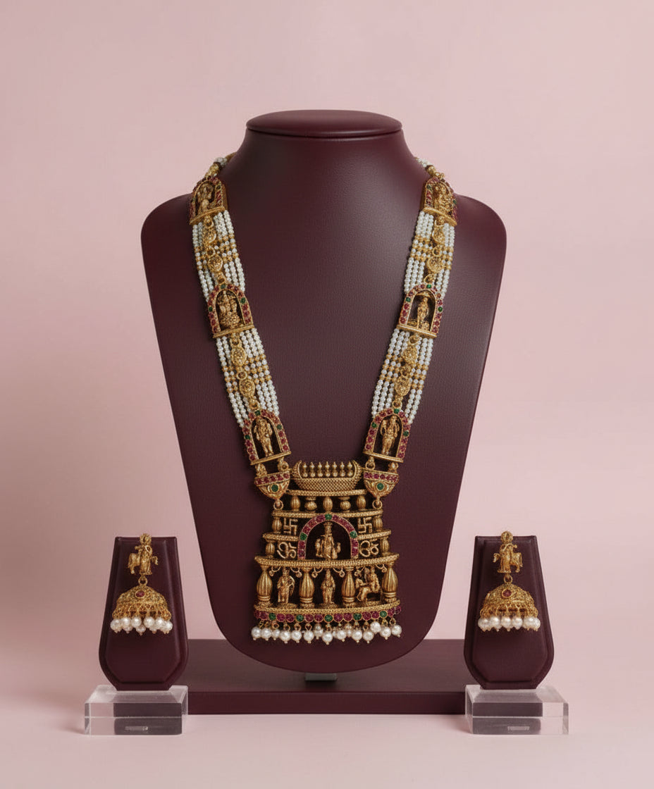 Gold necklace with matching earrings on a mannequin bust against a pink background